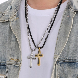Close-up of layered silver and gold-black cross necklaces on male model wearing denim jacket