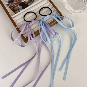 Elegant purple and light blue bow hair ribbons with long tassels on a wooden tray