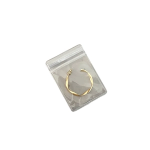 Golden twisted hoop earring in a transparent PVC jewelry storage bag on white background