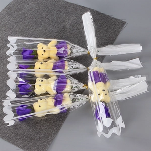 Close-up of five mini bear figurines holding purple soap roses in clear gift packaging