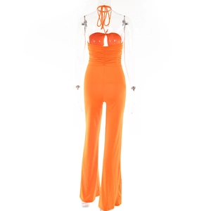 Detail view of orange halter jumpsuit showing backless design and ruched details