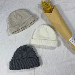 Flat lay of ribbed knit beanies in beige, cream and dark grey colors for winter season