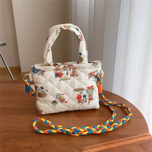 Detailed texture of quilted cream crossbody bag with cute animal prints and woven strap