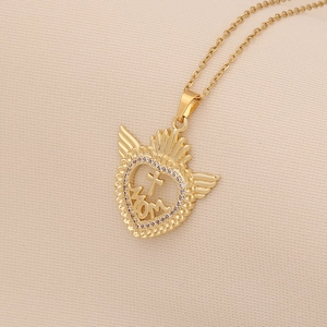Detail of golden heart pendant with crown, wings, cross and MOM engraving on necklace