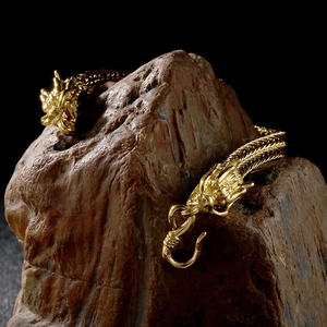 Detail of vintage gold dragon bracelet with scales wrapped on dark natural stone