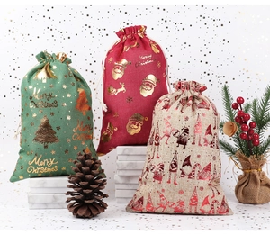 Detail of Christmas drawstring gift bags in green, red, and beige with gold foil prints