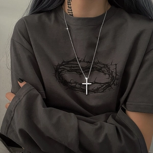 Polished silver cross pendant on thin chain shown on grey sweater for minimalist streetwear look