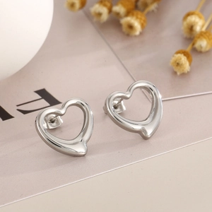 Macro detail of silver open heart stud earrings in a minimalist jewelry set
