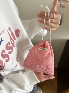 Pink pleated drawstring storage pouch held in hand for jewelry and cosmetics