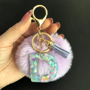 Détail d'un porte-clés à pompon violet avec lettre D et fermoir mousqueton doré