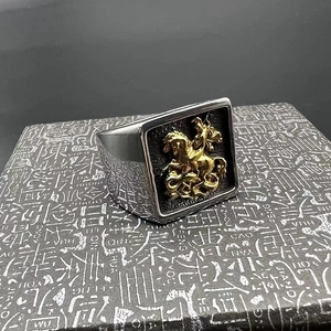 Détail macro d'une bague rétro en acier inoxydable avec relief doré de chevalier et dragon