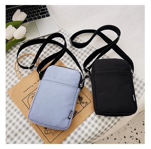 Top view of stylish black and light blue crossbody bags with adjustable straps on plaid fabric