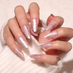 Pink cat eye almond press-on nails with gold leaf patterns on knitted background