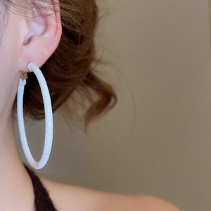 Close-up of white leather wrapped round hoop earring showing spiral texture on model