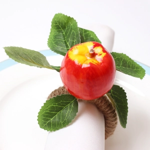 Macro detail of artificial red apple napkin ring with realistic leaves and jute rope texture