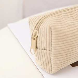 Detailed macro view of the cream corduroy texture and sturdy zipper of this pencil case