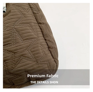 Macro shot of dark brown quilted fabric featuring star embroidery and pleated texture