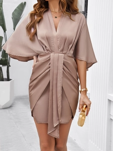 Detail of elegant champagne satin cocktail dress with V-neckline and draped waist knot