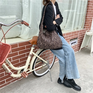 Outdoor street shot of large leopard print canvas shoulder bag with a vintage bicycle