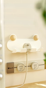 Macro view of cream frog-shaped power plug holder with four hooks for wire management