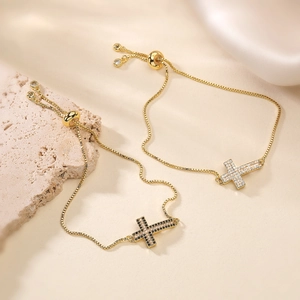 Vue détaillée de deux bracelets en or 18 carats avec pendentifs croix sertis de zircons