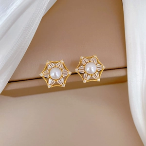 Macro view of gold hexagonal star stud earrings with white pearl and sparkling zircon