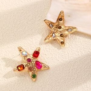 Detail of starfish earrings with colorful rhinestones on a sandy beach background