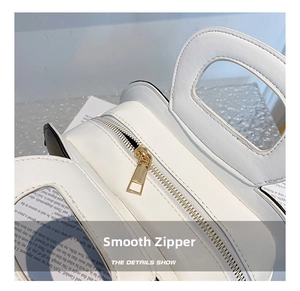 Detail shot of smooth gold-tone zipper and white leather finish on the crossbody bag