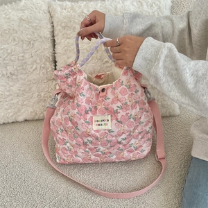 Detailed shot of pink floral quilted handbag with woven handles and brand label
