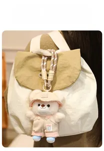 Detailed shot of a cute plush bear charm wearing pink overalls on a canvas backpack