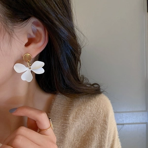 Gros plan de boucles d'oreilles fleurs blanches avec métal doré portées par un mannequin