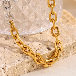 Detailed macro view of heavy 18K gold plated oval link chain on a beige stone
