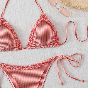 Detailed view of red and white striped bikini with ruffled edges and side tie accents