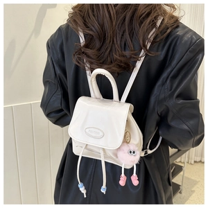 Dettaglio mini zaino in pelle PU bianca con ciondolo a pompon rosa e chiusura a coulisse