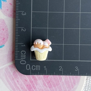 Detailed view of a 1.5cm miniature resin cupcake charm with pink sprinkles and cream topping