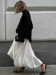 Minimalist white satin A-line maxi skirt paired with black knit top and pearl heels