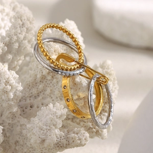 Close-up of 18K gold and silver pin-style stackable rings with zircons on coral