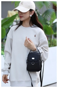 Outdoor street style shot of a woman wearing a black nylon multi-pocket crossbody bag
