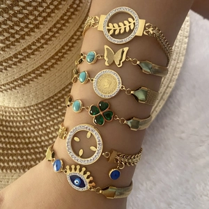Détail d'un ensemble de bracelets bohèmes dorés avec breloques œil, trèfle et papillon