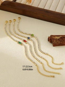 Detail view of gold flower bracelets with colorful gems on a wooden tray with size info
