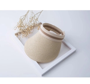 Dettaglio macro di un cappello da sole in paglia beige con nastro a righe marroni