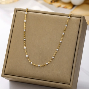 Bohemian gold plated stainless steel necklace with white enamel beads on an elegant display