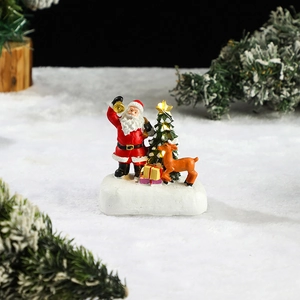 Detail of resin Santa Claus and reindeer figurines with glowing star tree on snow base