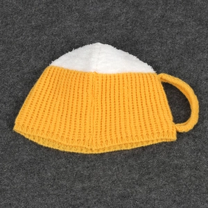 Detailed top view of a knitted beer mug hat with a yellow body and white foam texture
