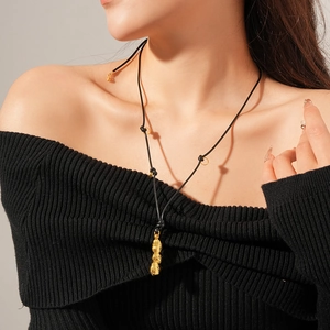Gros plan d'un collier avec pendentif cacahuète dorée porté sur un haut à épaules nues