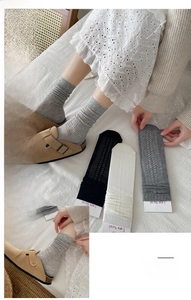 Detail of ribbed knit crew socks in grey, white, and black on a minimalist white bedding