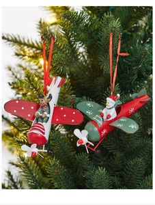 Close-up of metal airplane ornaments with deer and snowman on a Christmas tree branch