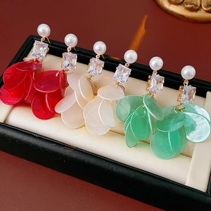 Makroaufnahme von Muschel-Fransenohrringen mit Zirkonia in Rot, Creme und Mintgrün