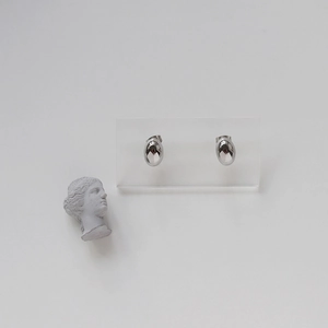 Macro shot of oval glossy silver titanium steel earrings with a reflective mirror finish