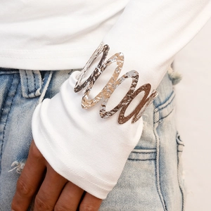 Detail of silver wavy hollow metal cuff bracelet with hammered texture on a wrist